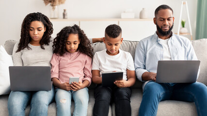 Focused african american family holding and using gadgets