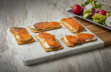 Smoked salmon crispbread toast with spread cheese, spices, and fresh salad