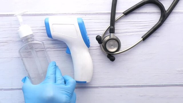 putting Surgical masks, thermometer and hand sanitizer on wooden table 
