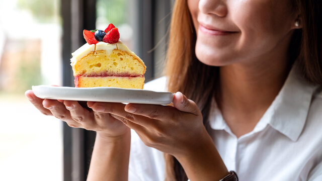 Closeup image of a beautiful young asian woman holding a piece of cake in a plate