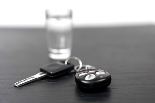 On the black table are the car keys and a shot of vodka close-up with copy space. Concept of drunk driving