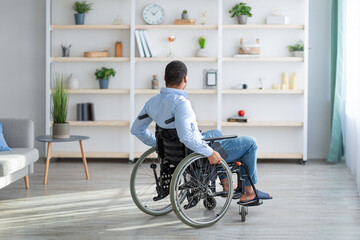 Depression in adults with disability. Unhappy young black man in wheelchair feeling lonely at home,...