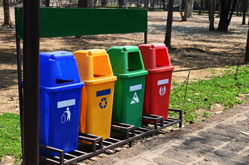 Fototapeta na wymiar The four large plastic bins are made up of Blue:general waste, Yellow:recycled waste, Green:wet waste, Red:hazardous waste.Bins are lined up in the park with an empty banner on top and marked at tank 