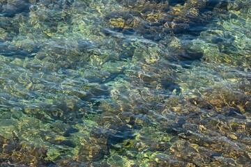 Fototapeta na wymiar rippled water surface and stone ground at the Mediterranean sea in abstract close up