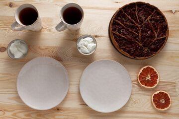 Whole quince stuffed pie ready to be served with yoghurt. Two plates and cups of tea.