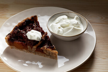 Piece of quince stuffed pie served with yoghurt. Close-up view of homemade dessert.