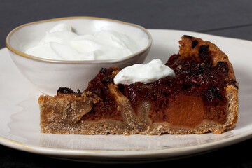 Piece of quince stuffed pie served with yoghurt. Close-up view of homemade dessert.