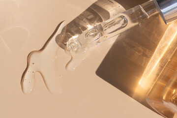close up of pipette with pouring liquid serum with golden bottle and shadows - obrazy, fototapety, plakaty
