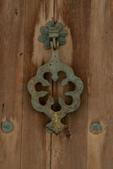 old metal door knock ornamental on a wooden exterior door close up