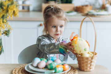 Cute adorale baby girl plays with colorful easter eggs at home