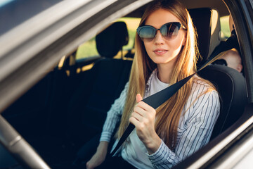 Close up portrait of young woman, content with travel by car, sitting on driver's seat