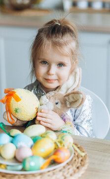 Cute adorale baby girl plays with colorful easter eggs at home