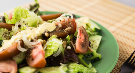 vegetable salad of greens, tomatoes and cucumbers on a green plate