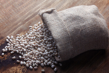 Fototapeta na wymiar Raw grains fradinho beans in rustic bag on wooden table