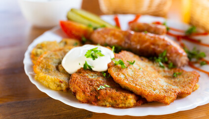 potato pancakes with fried sausages on a white plate