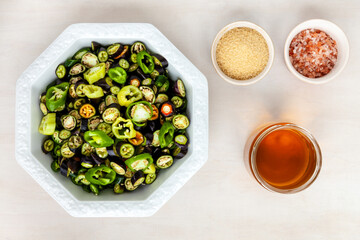 Bowl with cut spicy peppers (various cultivars) and other ingredients to make sliced pickled chillies, top view.