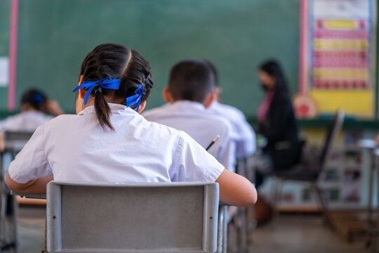 Close up of Writing test in exam with behind child asian students group concentrate in primary school, final examination desk at classroom with Thai student uniform, Education evaluation concept