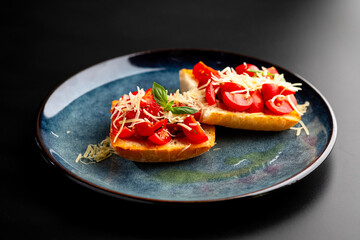 Bruschetta with mushrooms and tomatoes on a blue plate, on a black background.