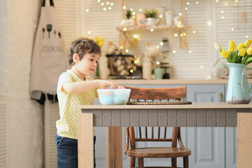 little boy puts colored eggs in a wicker Easter basket. easter preparation concept