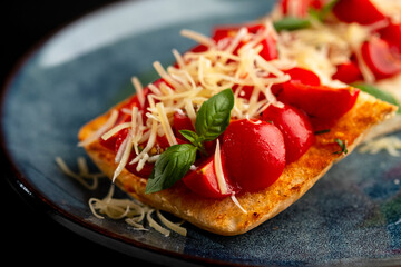 Bruschetta with mushrooms and tomatoes on a blue plate, on a black background.