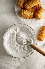 cream meringue, whipped egg whites, whipped cream in a cooking bowl with a whisk