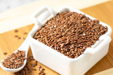 Brown flax seeds in a white bowl on a light background
