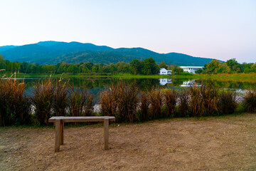 wood bench with beautiful lake at Chiang Mai with forested mountain and twilight sky