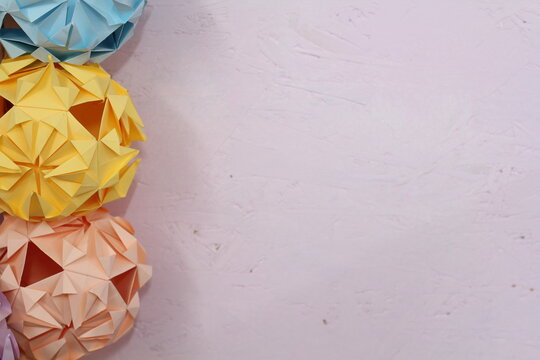 A border of paper origami spheres on a pastel painted wall , wedding or celebration decorations 
