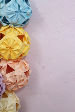 Origami paper balls hanging on a pastel painted wall , a decorative border , suitable for wedding or celebrations decorations. 