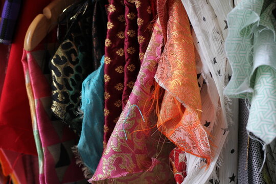 Vintage fabrics , including sari silks hanging up to be used for up cycling . 