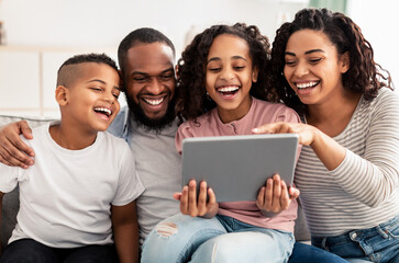 Happy African American family using tablet sitting on the couch