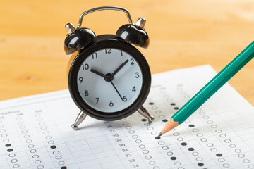 alarm clock, optical form of standardized school test with bubble and black pencil, answer sheet, education concept