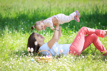 Cheerful mother having fun with her little daughter in Easter day, nature background. Single...