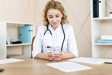 Woman doctor in white coat using modern smartphone