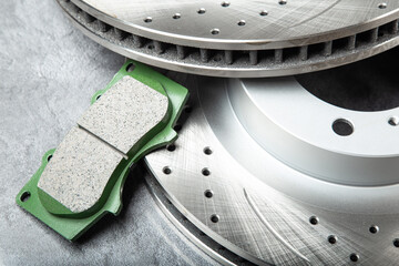 brake pads and perforated brake discs on a stone gray table