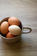 Ceramic bowl filled with fresh free range eggs on wooden table. Selective focus.