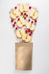 Healthy breakfast and snack concept. Top view of granola ingredients apple sunflower seeds raspberry flax seeds oatmeal fall into paper bag on white background