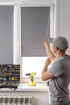 Man Installing Gray Roller Blinds On The Window