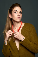 Studio portrait of a woman holding a red pearls necklace.