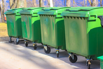 Large green plastic trash cans on city street. Containers on wheels with a handle to collect...