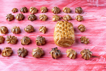 Homemade eclairs and jam puff on a wooden background.