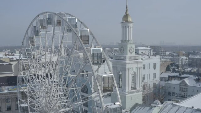 Kiev. Drone video. The big white Ferris wheel and tourists walking in the center of Kontraktova Square in the Podolsk district of Kiev. Winter morning.