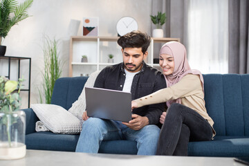 Family leisure, technology concept. Lovely happy young arabic muslim couple in casual domestic...