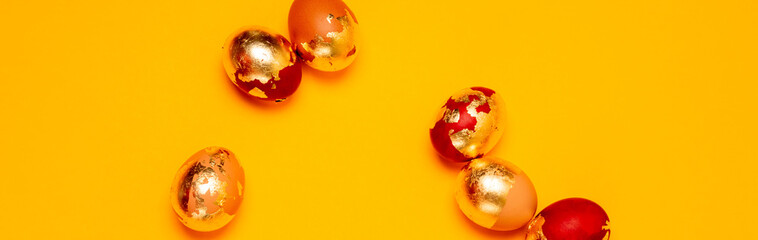 Happy Easter web banner. Golden chicken eggs on a yellow background. Top view, flat lay with copy space.