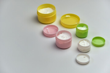 multi-colored jars with white cosmetic cream for face