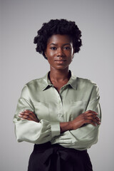 Obraz premium Studio Portrait Of Serious Young Businesswoman With Folded Arms Against Plain Background