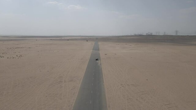Aerial view of black car speeding on desert road near Dubai United Arab Emirates