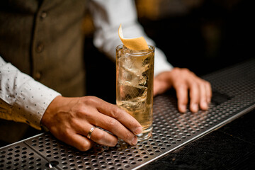 great view on glass with cold drink decorated with citrus peel on bar counter