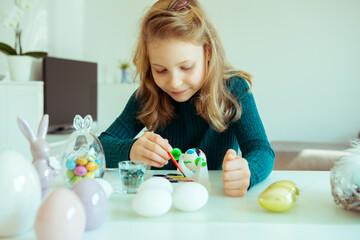 Cute little blonde girl painting Easter eggs