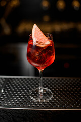 beautiful wine glass with bright cold iced drink decorated with citrus slice on bar
